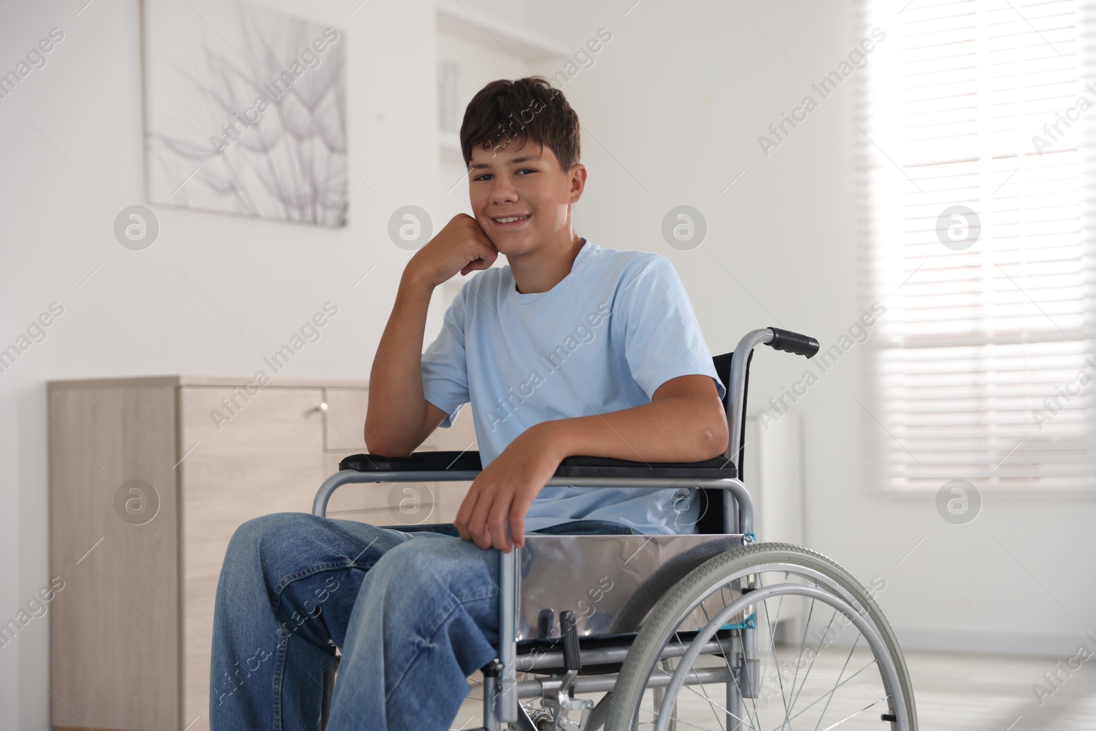 Photo of Happy teenage boy in modern wheelchair indoors