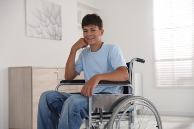 Photo of Happy teenage boy in modern wheelchair indoors