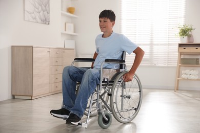 Photo of Happy teenage boy in modern wheelchair indoors