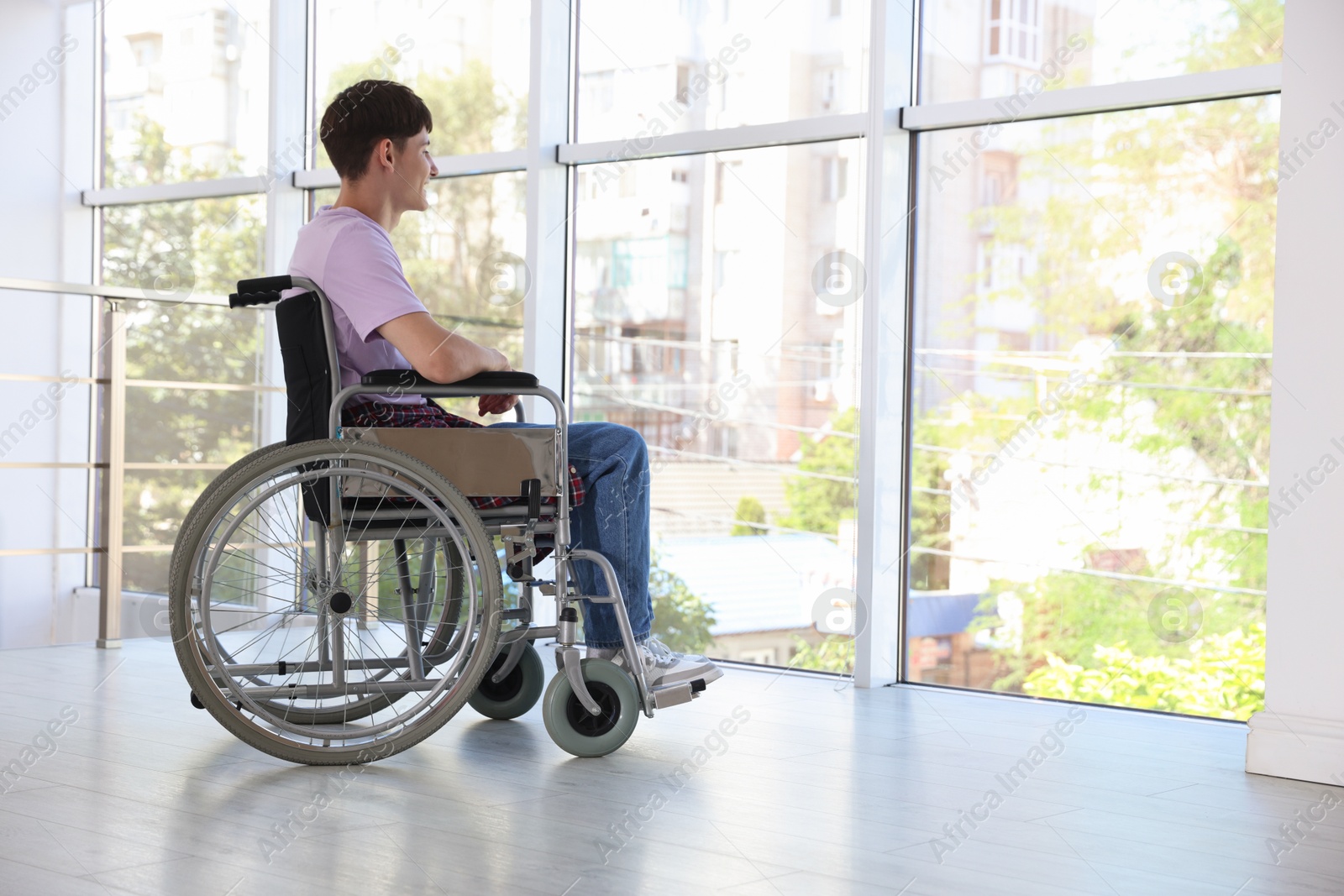 Photo of Young man in modern wheelchair indoors, space for text
