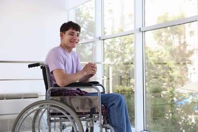 Photo of Happy young man in modern wheelchair indoors, space for text