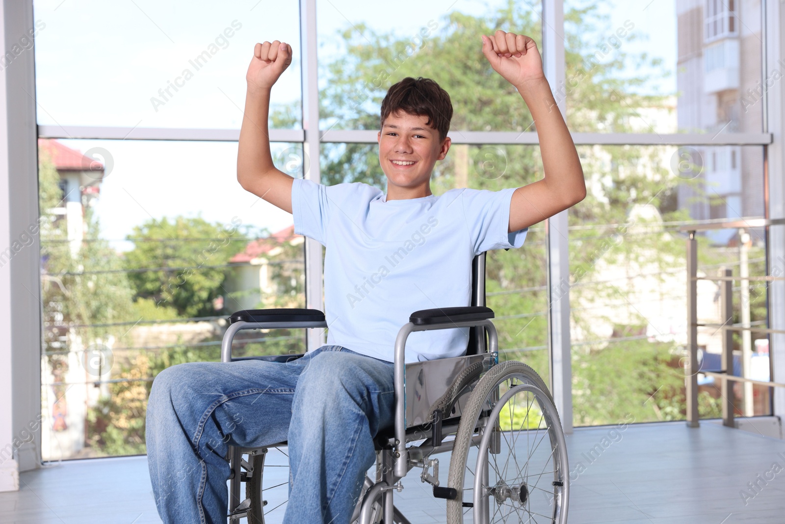Photo of Happy teenage boy in modern wheelchair indoors