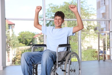 Photo of Happy teenage boy in modern wheelchair indoors