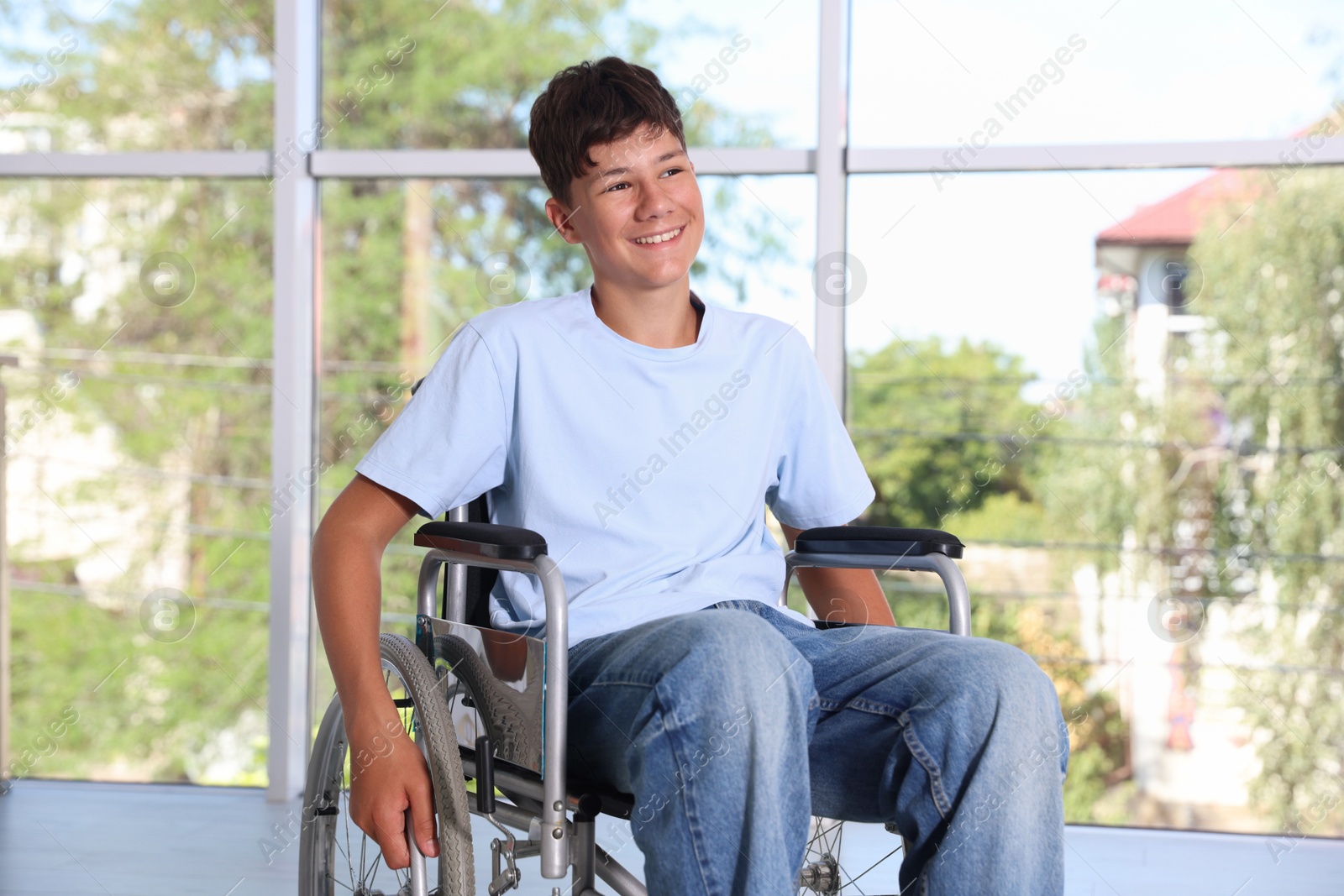 Photo of Happy teenage boy in modern wheelchair indoors