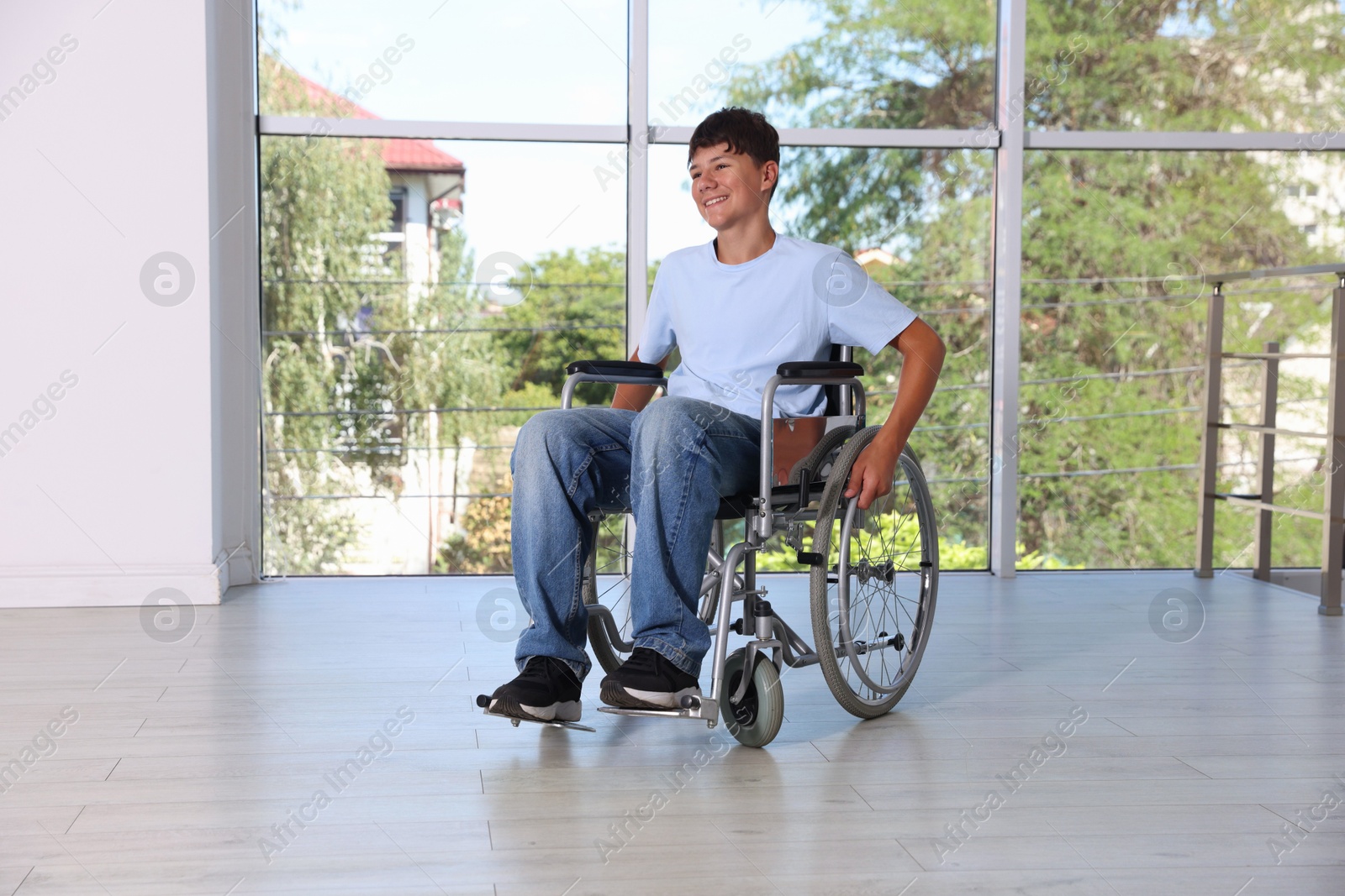 Photo of Happy teenage boy in modern wheelchair indoors