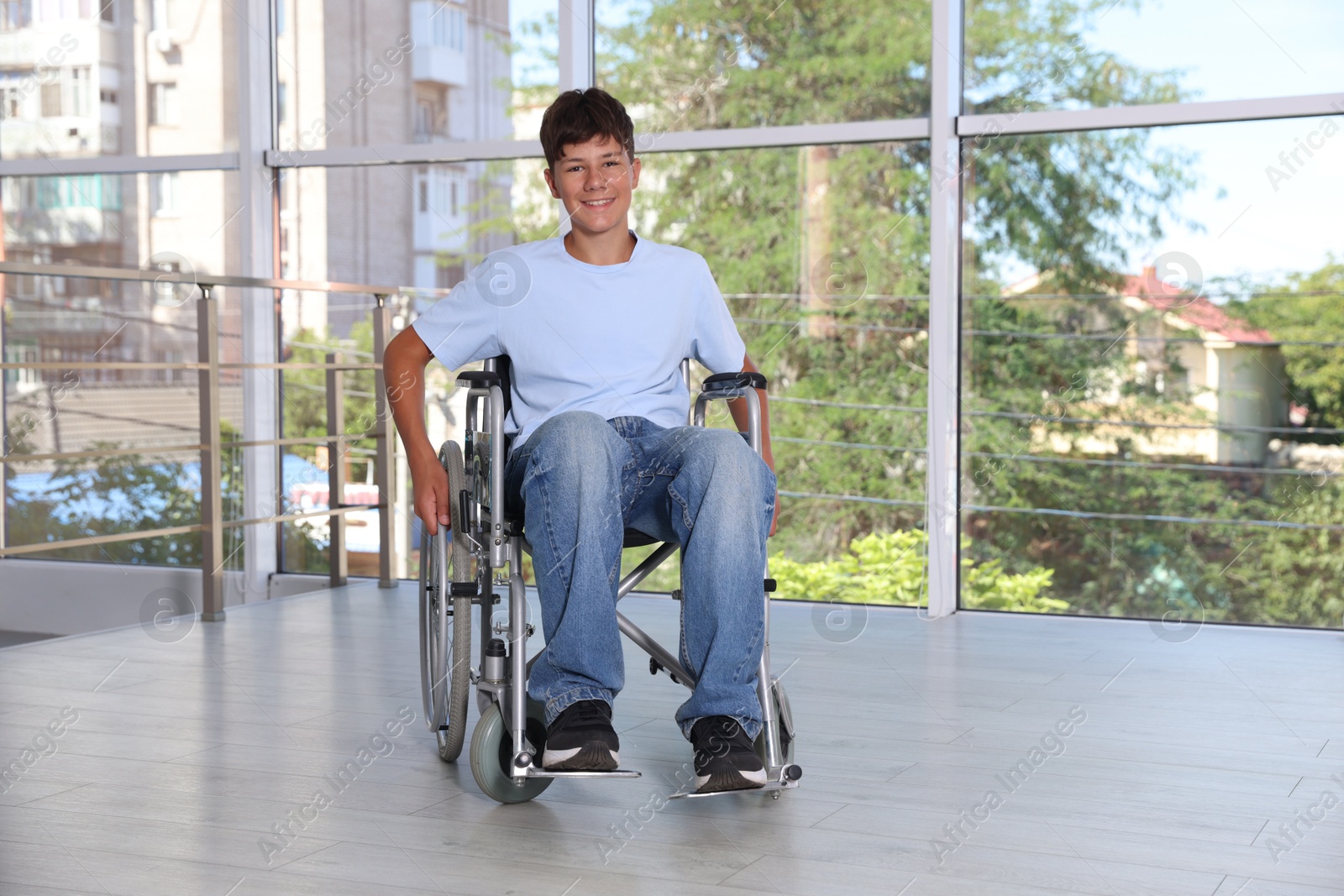 Photo of Happy teenage boy in modern wheelchair indoors