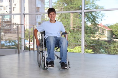 Photo of Happy teenage boy in modern wheelchair indoors