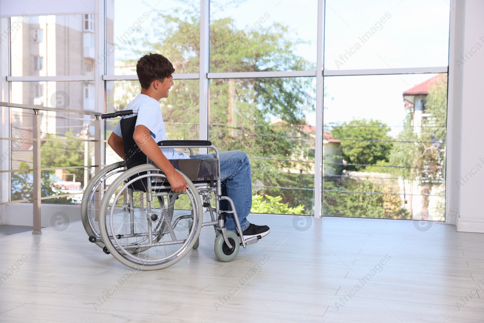Photo of Teenage boy in modern wheelchair indoors, space for text
