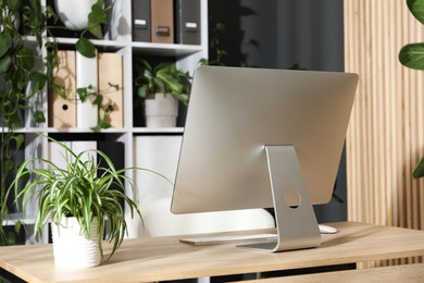 Photo of Stylish workplace with modern computer and floral decor in office. Biophilic interior design