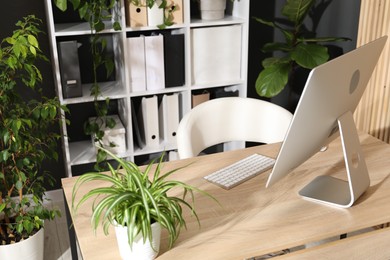 Photo of Stylish workplace with modern computer and floral decor in office. Biophilic interior design