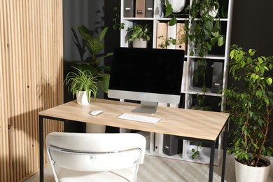 Photo of Stylish workplace with modern computer and floral decor in office. Biophilic interior design