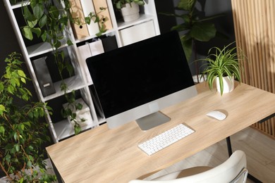Photo of Stylish workplace with modern computer and floral decor in office. Biophilic interior design