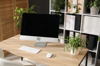 Photo of Stylish workplace with modern computer and floral decor in office. Biophilic interior design