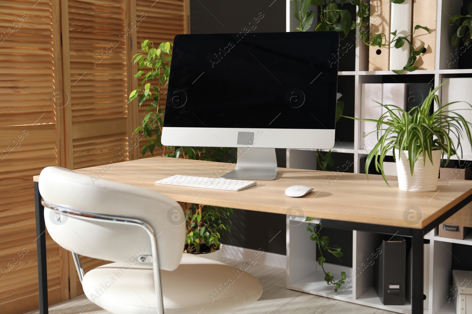 Stylish workplace with modern computer and floral decor in office. Biophilic interior design Photo of Stylish workplace with modern computer and floral decor in office. Biophilic interior design