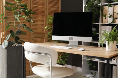 Photo of Stylish workplace with modern computer and floral decor in office. Biophilic interior design