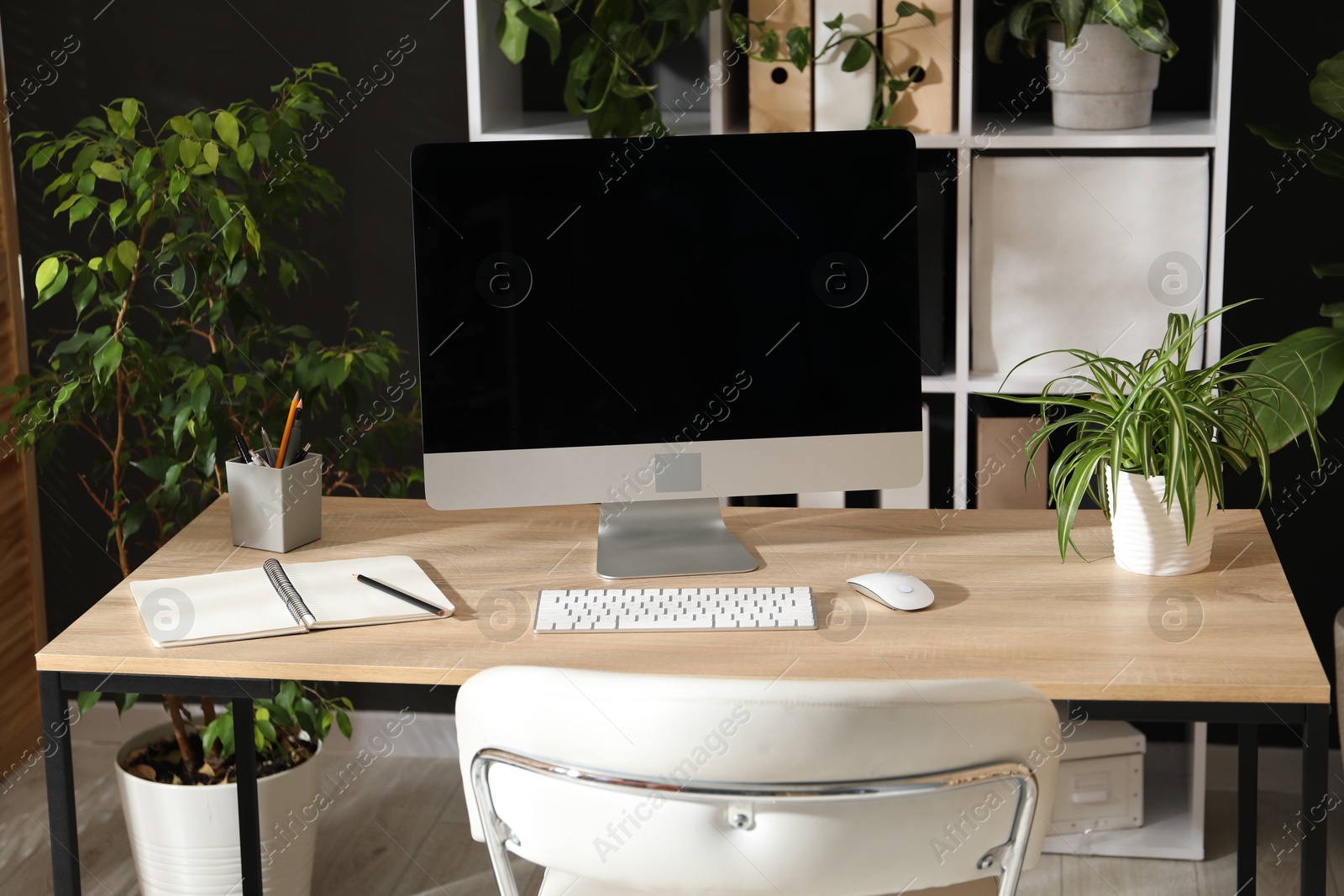 Stylish workplace with modern computer, stationery and floral decor in office. Biophilic interior design Photo of Stylish workplace with modern computer, stationery and floral decor in office. Biophilic interior design