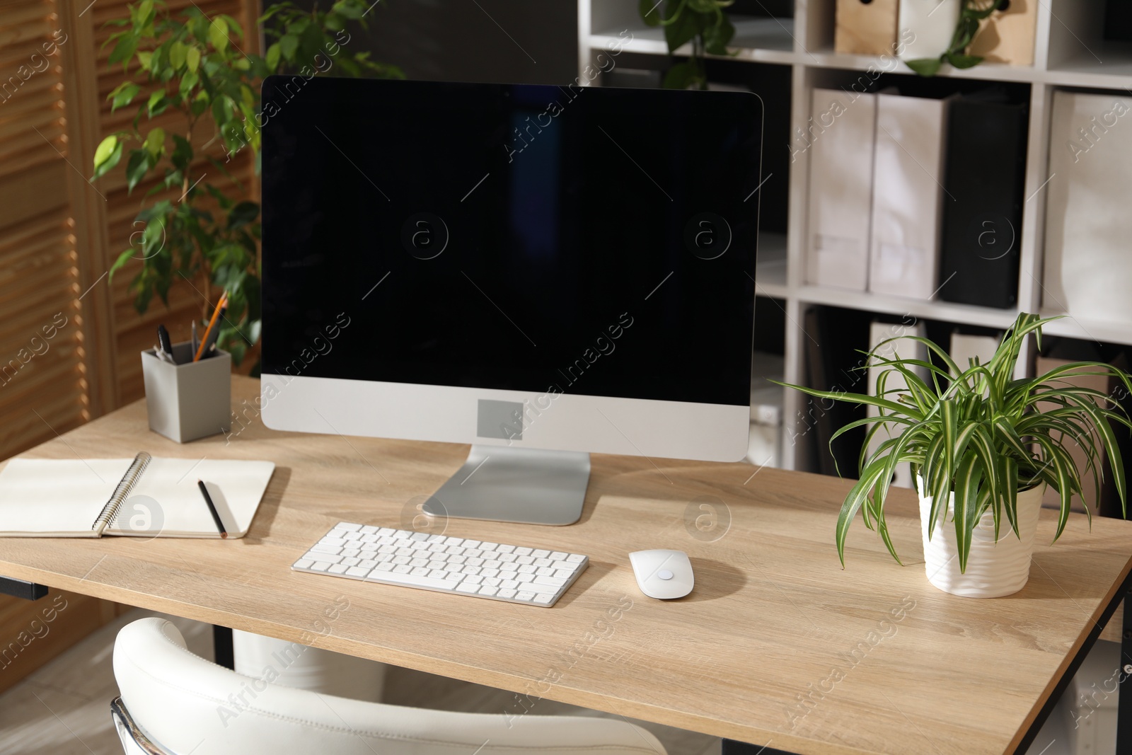 Stylish workplace with modern computer, stationery and floral decor in office. Biophilic interior design Photo of Stylish workplace with modern computer, stationery and floral decor in office. Biophilic interior design
