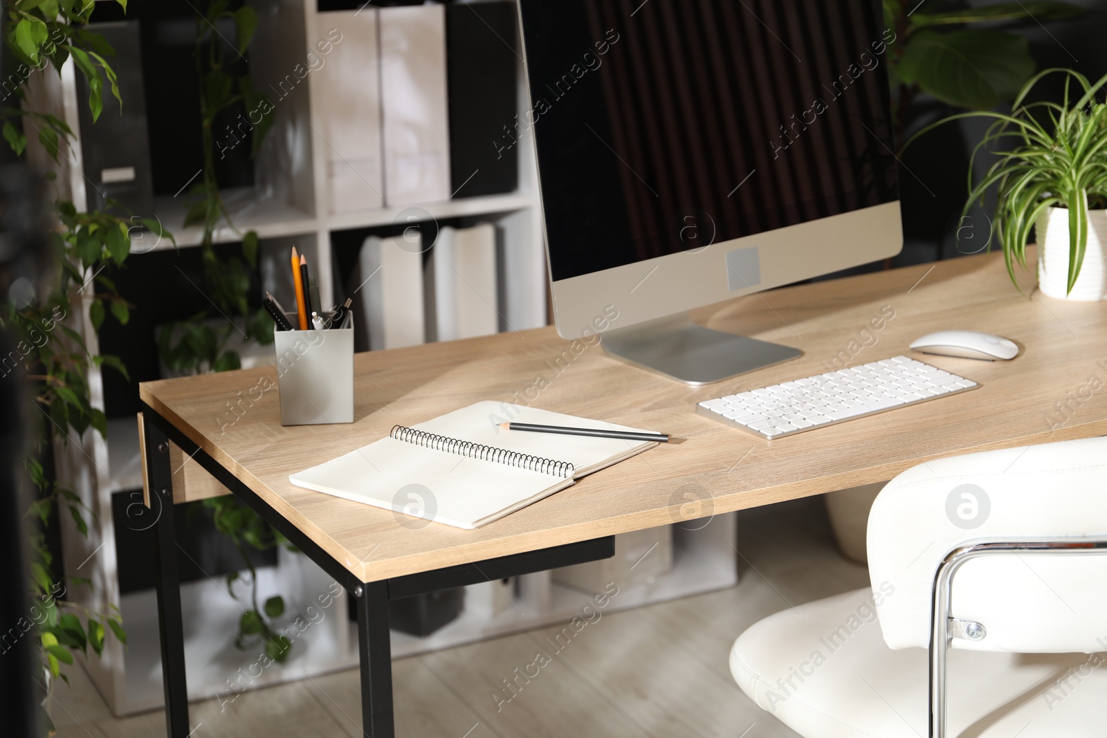 Stylish workplace with modern computer, stationery and floral decor in office. Biophilic interior design Photo of Stylish workplace with modern computer, stationery and floral decor in office. Biophilic interior design