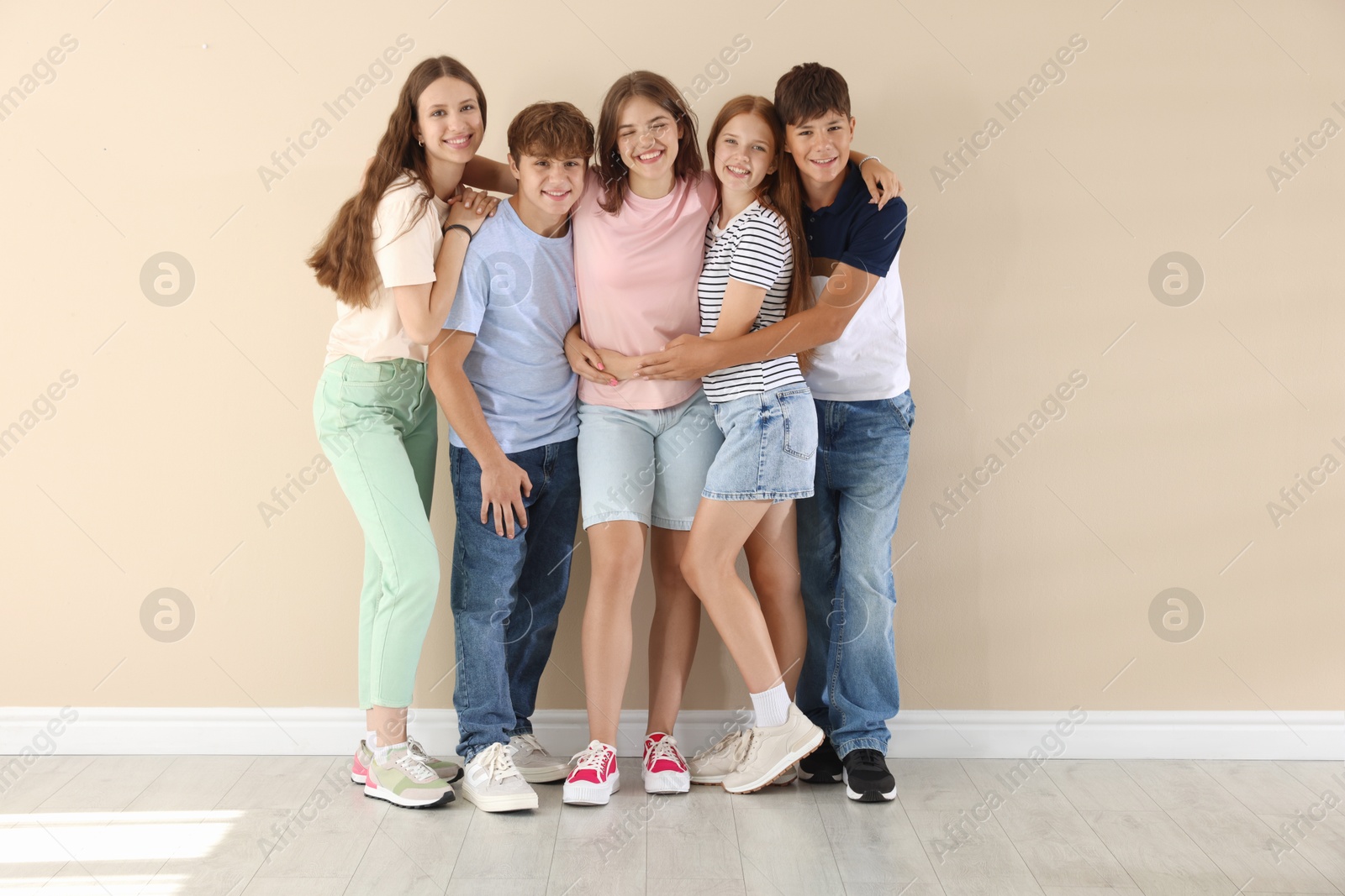 Photo of Happy teenage friends near beige wall indoors