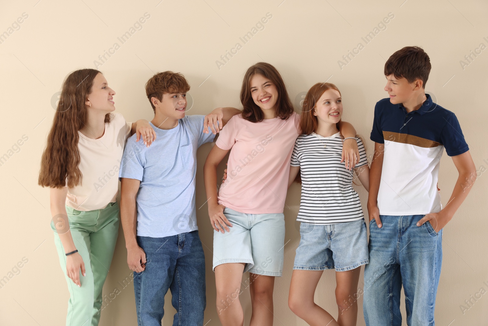 Photo of Portrait of happy teenage friends on beige background