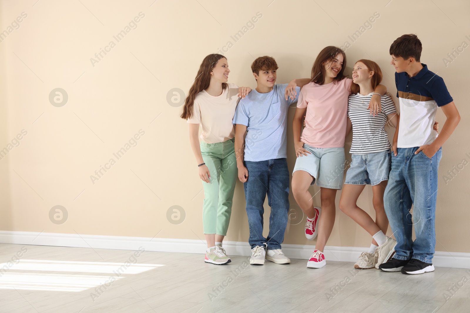 Photo of Happy teenage friends near beige wall indoors