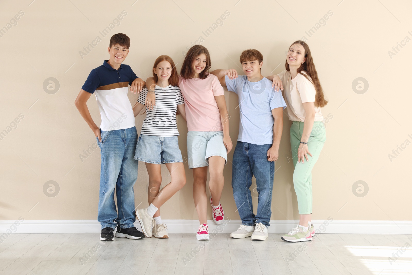 Photo of Happy teenage friends near beige wall indoors