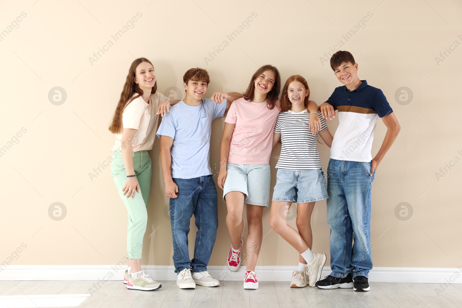 Photo of Happy teenage friends near beige wall indoors