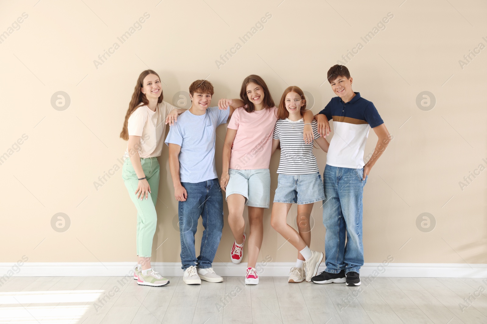 Photo of Happy teenage friends near beige wall indoors