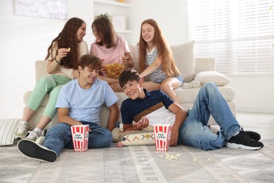 Photo of Happy teenage friends with snacks watching movie indoors