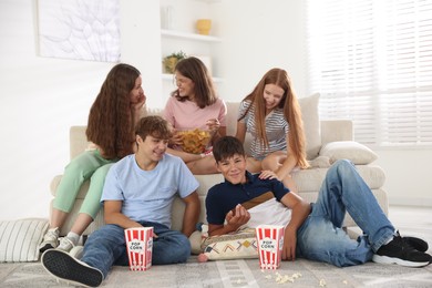 Photo of Happy teenage friends with snacks watching movie indoors