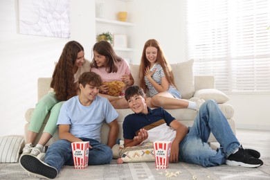 Photo of Happy teenage friends with snacks watching movie indoors