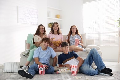 Photo of Happy teenage friends with snacks watching movie indoors