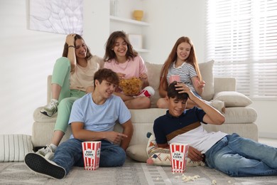 Photo of Happy teenage friends with snacks watching movie indoors