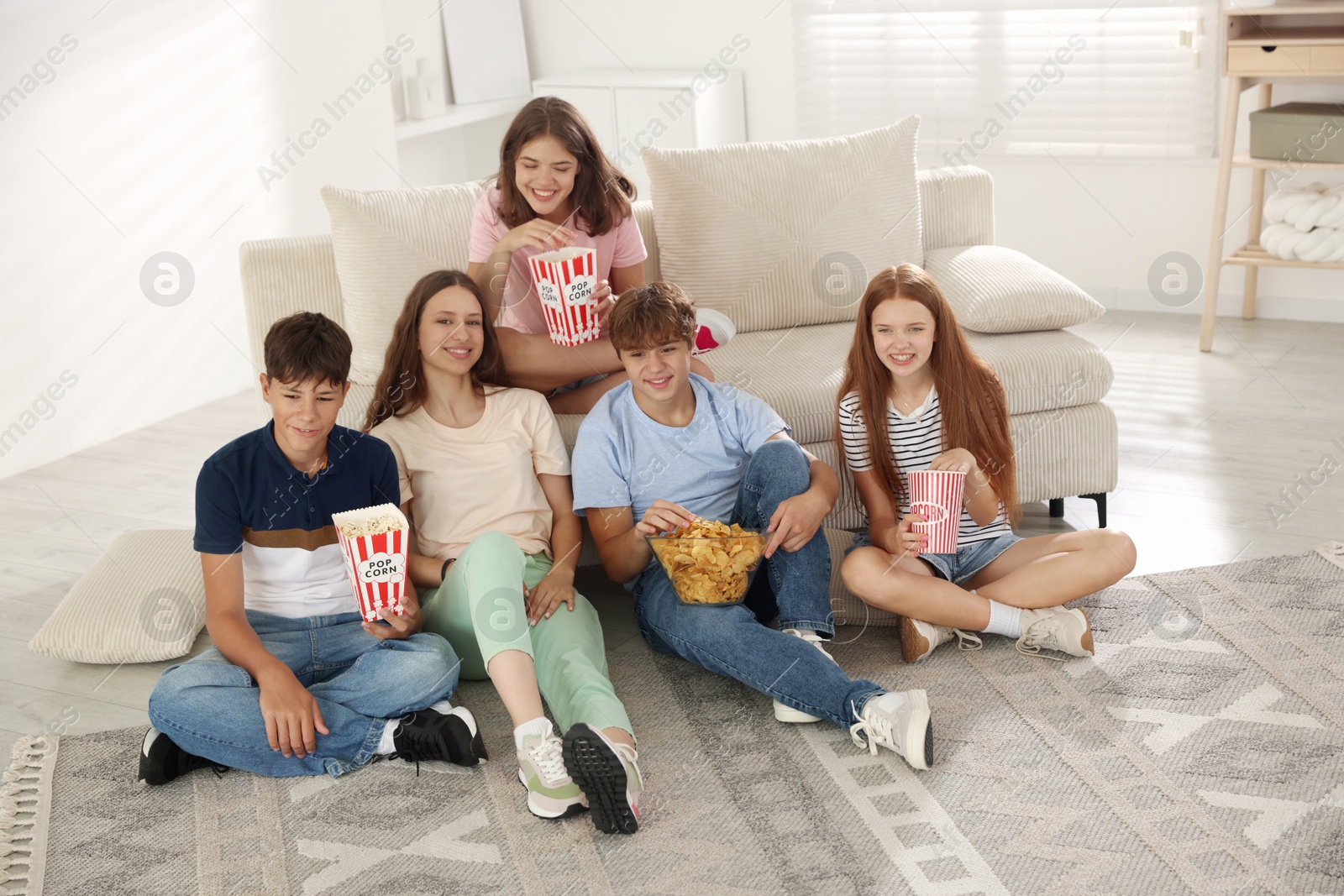 Photo of Happy teenage friends with snacks watching movie indoors