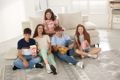Photo of Happy teenage friends with snacks watching movie indoors