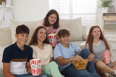 Photo of Happy teenage friends with snacks watching movie indoors