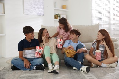 Photo of Happy teenage friends with snacks watching movie indoors