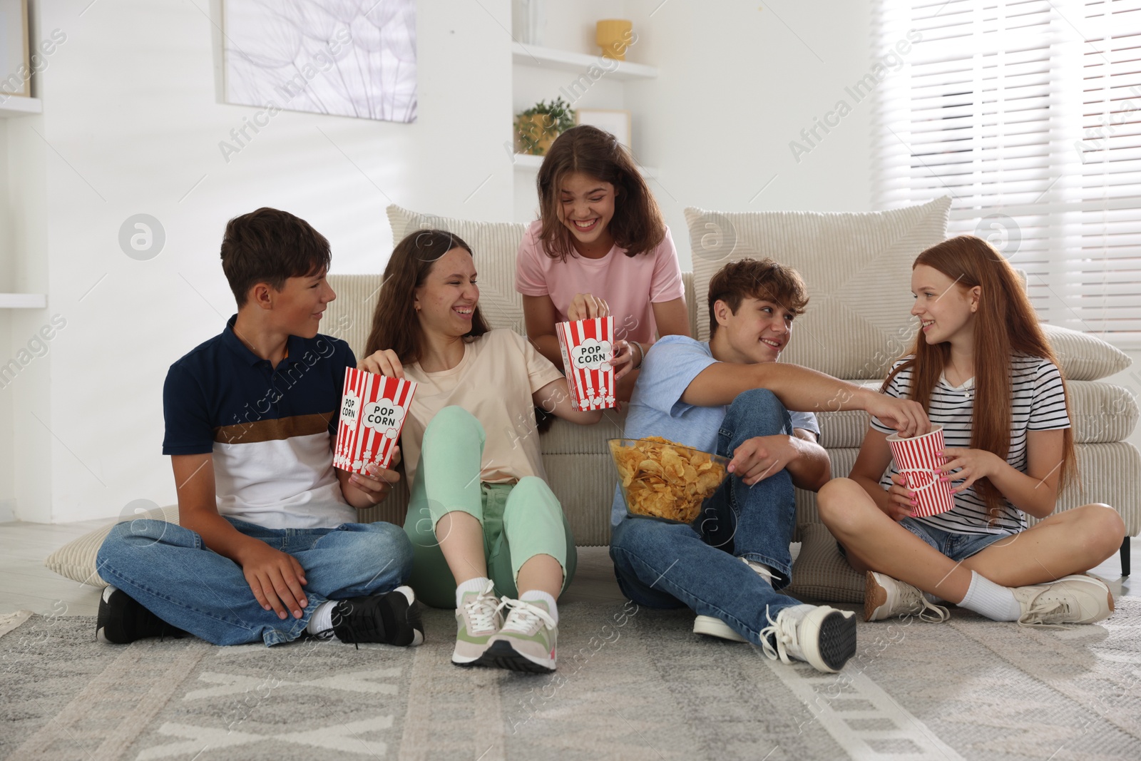 Photo of Happy teenage friends with snacks watching movie indoors