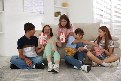 Photo of Happy teenage friends with snacks watching movie indoors