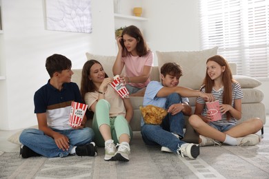 Photo of Happy teenage friends with snacks watching movie indoors