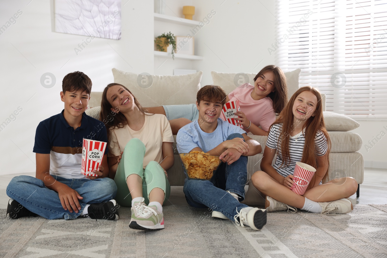 Photo of Happy teenage friends with snacks watching movie indoors