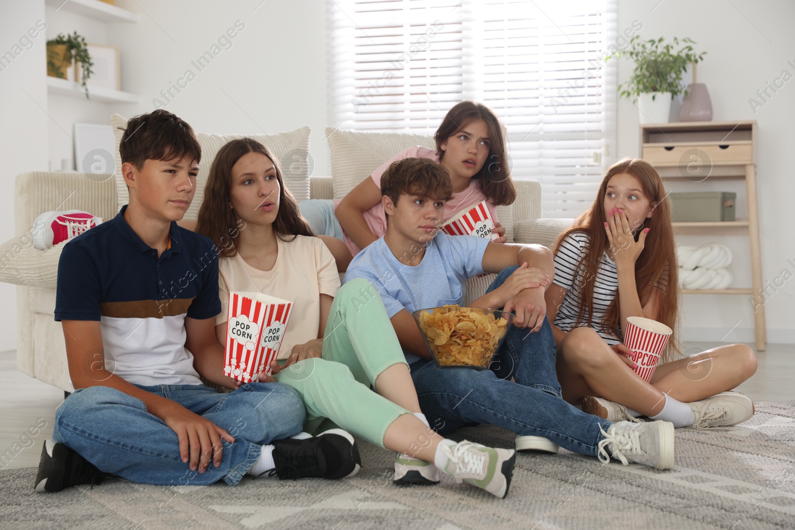 Photo of Teenage friends with snacks watching movie indoors