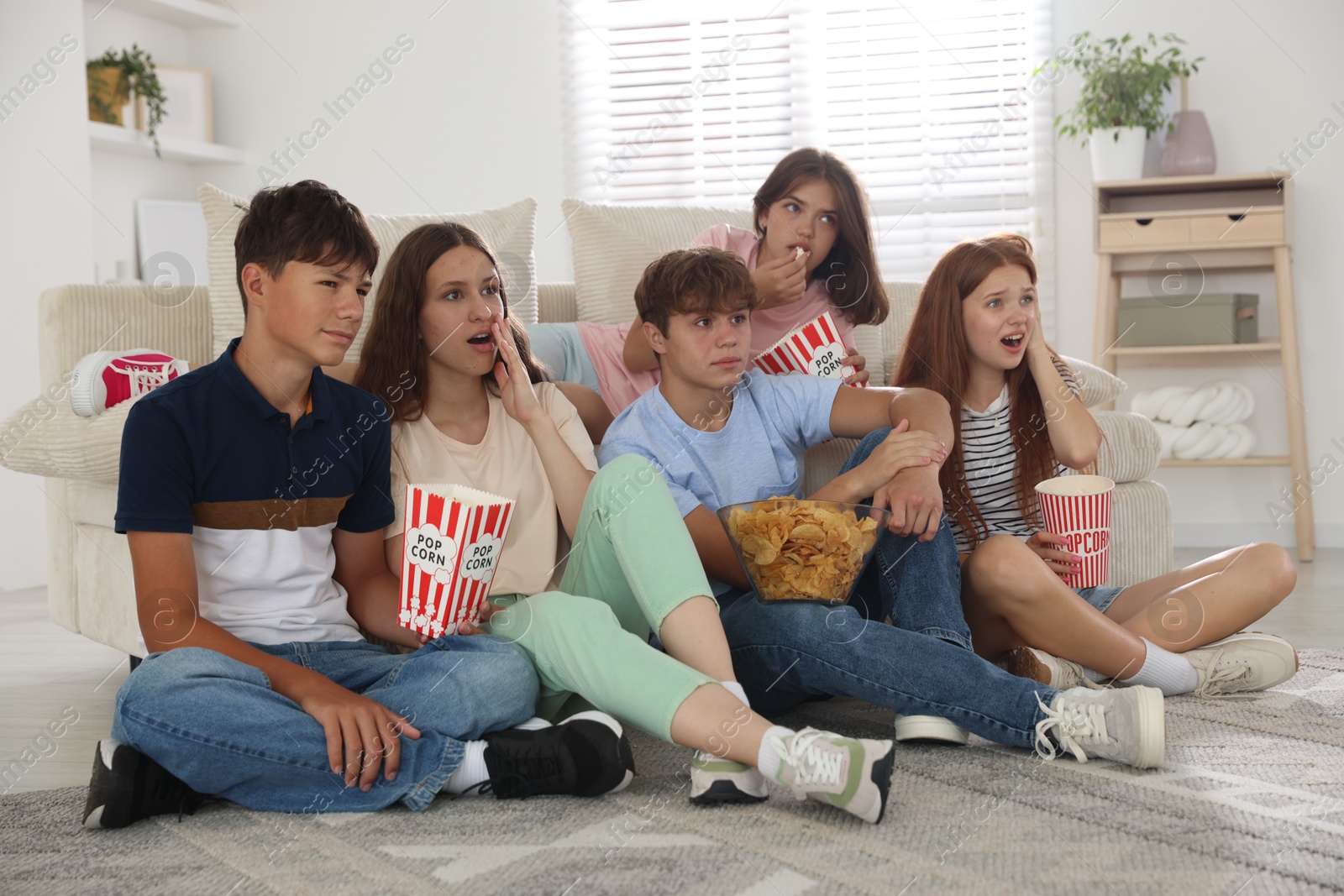 Photo of Teenage friends with snacks watching movie indoors