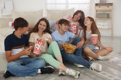 Photo of Happy teenage friends with snacks watching movie indoors