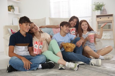 Photo of Happy teenage friends with snacks watching movie indoors