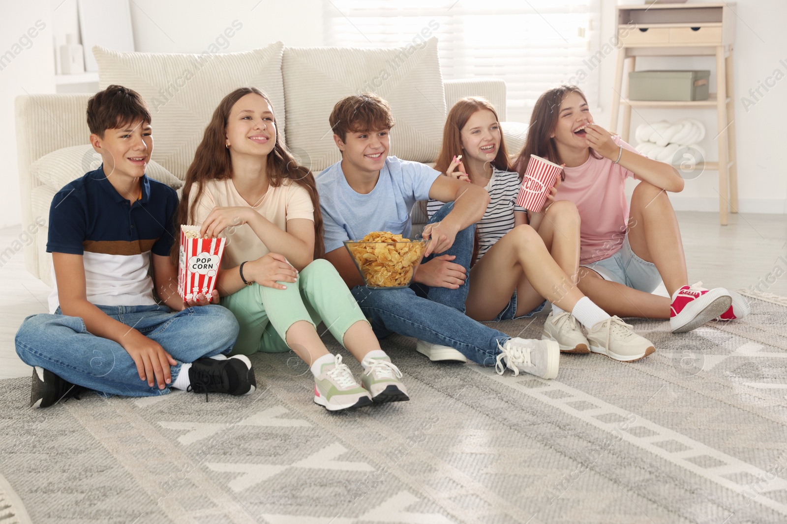 Photo of Happy teenage friends with snacks watching movie indoors