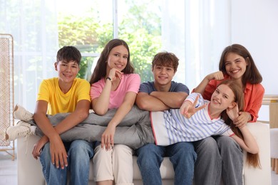 Photo of Happy teenage friends sitting on sofa indoors