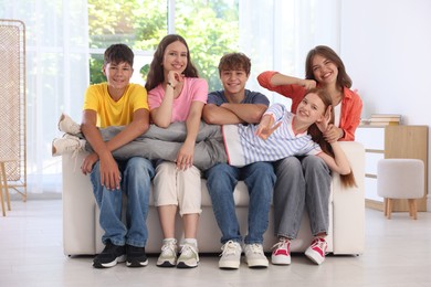 Photo of Happy teenage friends sitting on sofa indoors