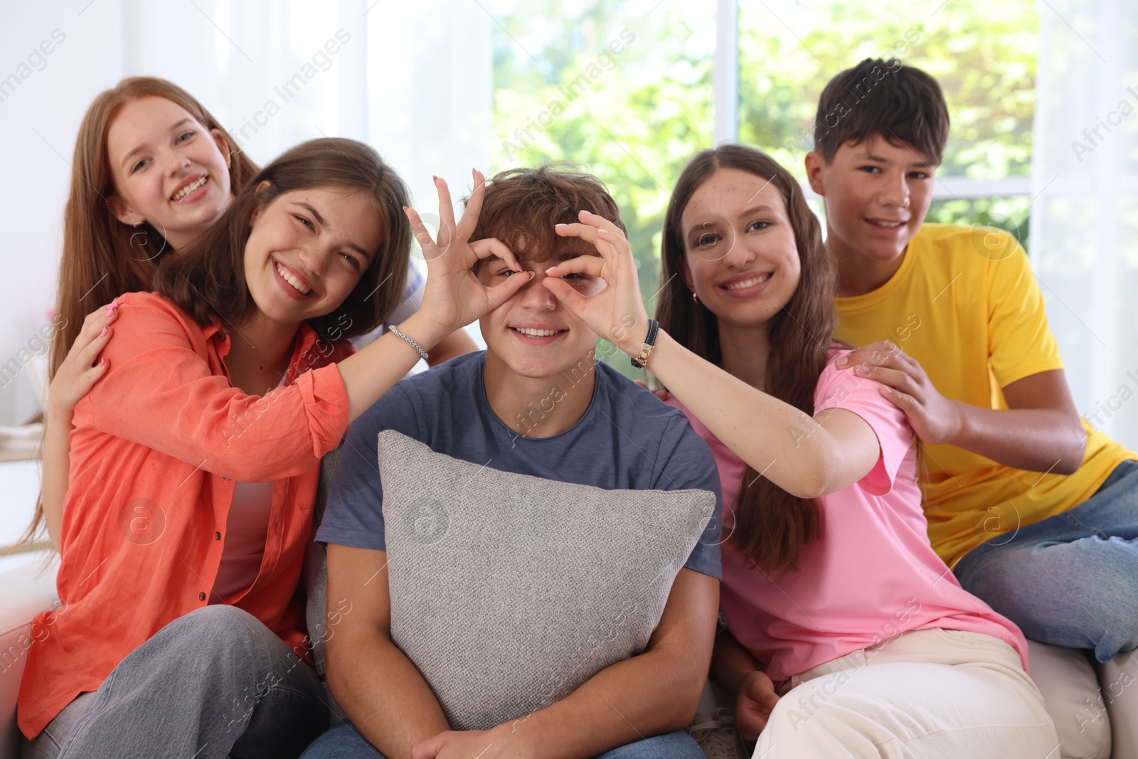 Photo of Happy teenage friends sitting on sofa indoors