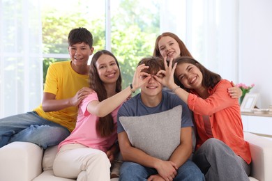 Photo of Happy teenage friends sitting on sofa indoors